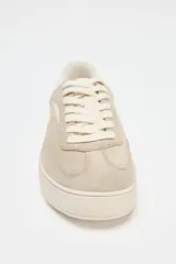 Zapatillas deportivas color beige, con suela alta de 3 cm y cierre con cordones.