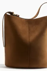 Cartera bombonera marrón de gamuza con correa ajustable y asa de hombro.