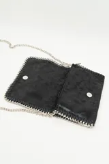 Cartera de mano negra con textura y correa de cadena plateada.
