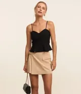 Blusa estilo corset color beige, confeccionada en crepé, con breteles finos, escote corazón, cremallera en la espalda y volado peplum en el bajo.
