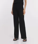 Pantalón negro de punto, modelo wide leg, con cintura elástica y superficie lisa.