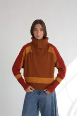 Buzo de punto color marrón con detalles en naranja, cierre frontal parcial y cuello polo.