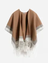 Ruana de color tostado con diseño de guarda en el borde inferior en tonos gris y blanco, terminada con flecos largos en color blanco.