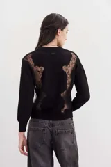 Sweater negro de punto con cuello redondo y mangas largas. Presenta recortes de encaje en la parte superior delantera y en los hombros.
