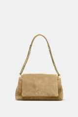 Bolso de hombro color beige, confeccionado en piel de serraje. Tiene correa metálica con detalles, pespuntes en el cuerpo, múltiples bolsillos con cierre de cremallera metálica, cierre imantado y solapa.