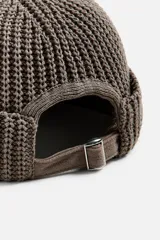 Gorro negro corto de punto con ajuste con trabilla y acabado con vuelta.