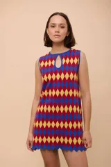 Vestido corto sin mangas con estampado de rombos en amarillo, azul y rojo. Tiene escote con abertura en forma de gota y ruedo con terminación en picos.