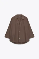 Camisa marrón de popelina con cuello solapa, escote en pico, cierre frontal con botones y mangas anchas con puños.