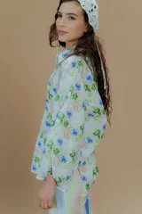 Camisa de mangas largas con puños elásticos y cuello clásico. Presenta un estampado a rayas verticales de colores pastel y cierre frontal con botones.