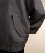 Campera gris con capucha, cuello alto, mangas largas y bolsillos con solapa y botones. Cierre frontal oculto. Marca Request, colección Primavera/Verano 2024.