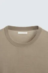 Jersey de hombre color beige claro, tejido en lana, de corte recto, cuello redondo y mangas largas con terminaciones en rib.