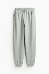 Pantalón de jogging color gris claro, de tiro alto, con cintura elástica ajustable con cordón, bolsillos laterales y puños elásticos.