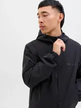 Campera softshell negra con capucha ajustable con cordón, mangas largas con puños de canalé, cierre frontal con cremallera y bolsillos delanteros. Forro sin relleno y costuras cubiertas.