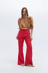 Conjunto de blazer y pantalón acampanado color rojo. El blazer es de corte clásico con solapas y un botón, y tiene volados en las mangas. El pantalón es de tiro alto y pierna acampanada.