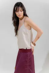 Musculosa de lino color crudo con rayas verticales finas en negro, escote en V y breteles finos regulables con detalle de borlas.