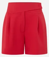 Bermuda sastre de poliéster color rojo, de tiro alto, con cintura asimétrica cruzada, pliegues frontales y bolsillos laterales.