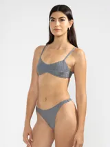 Conjunto de bikini color rosado con textura acanalada. El corpiño es de corte triangular con tirantes finos y la bombacha es tipo colaless.