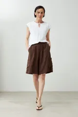 Remera blanca de manga corta con cuello redondo y un pequeño corte en forma de 'V' en el centro del escote. Presenta bordados blancos en el área del pecho y hombros.