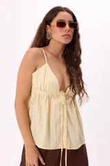 Top color amarillo pálido con breteles finos, escote en V profundo y ajuste frontal con botones.