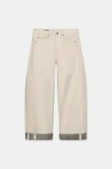 Jeans de tiro medio color beige, corte relaxed leg y largo al tobillo. Cuentan con cinco bolsillos y bajo con vuelta a contraste en gris. Cierre frontal con cremallera y botón.