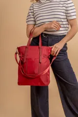 Cartera tipo tote bag color negro, con doble asa de mano y correa bandolera ajustable. Presenta un bolsillo rectangular en el frente.