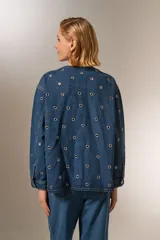 Campera de jean azul con manga larga, corte holgado, cuello redondo y cierre frontal con botones. Presenta bolsillos delanteros y detalles de ojales metálicos.