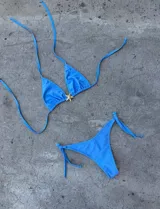 Conjunto de bikini color crema con corpiño triangular con detalle de estrella dorada y bombacha con tiras laterales.