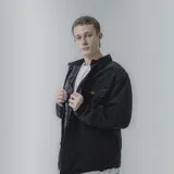 Campera negra de pana con cuello camisero, cierre frontal con botones a presión, dos bolsillos de parche en el pecho y corte recto.