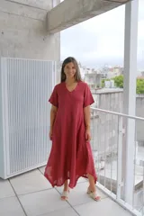 Vestido de manga corta, color rojo oscuro (bordeaux), con escote en V y corte acampanado que termina en un bajo asimétrico con detalle deshilachado.