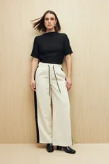 Pantalón de jogging color crema con cintura elástica, cordón ajustable y franja lateral negra.