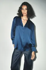 Camisa azul marino de satén con cuello solapa, escote en pico y mangas largas con puños abotonados.