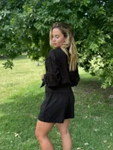 Conjunto negro de camisa de manga larga con botones y shorts.