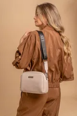 Bandolera pequeña de textura símil cuero color caramelo/marrón, con dos compartimentos principales con cierre. Correa ancha ajustable de tela negra con inscripción en relieve.