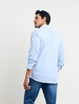 Camisa celeste de manga larga con cuello button-down, confeccionada en tejido rústico de algodón y lino.