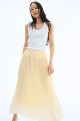 Pollera larga color amarillo pálido, de gasa plisada, con cintura alta con elástico fino y forro interior.