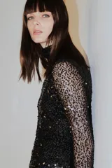 Vestido largo negro de red con lentejuelas y cuello alto.