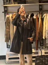 Trench de cuero color bordó, con cuello clásico, cierre frontal con botones y bolsillos laterales.