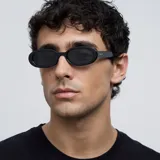 Lentes de sol unisex, con montura ovalada negra y lentes polarizadas negras.