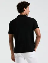 Polo negra de piqué de algodón orgánico, corte recto, cuello con solapa y logo bordado en el pecho.
