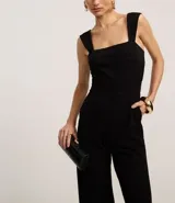 Mono largo de crepé color negro, con escote cuadrado, breteles anchos, bolsillos laterales y cierre trasero con cremallera.