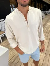 Camisola de lino color beige, con cuello mao y mangas largas con puños abotonados.