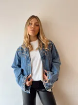 Campera de jean celeste con apliques de estrellas doradas en cuello, hombros y puños.