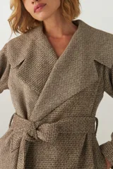 Tapado largo color beige con diseño de espiga, cuello solapa, cierre cruzado con cinturón y bolsillos laterales. Confeccionado en lana fina sin teñir.