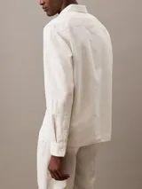 Camisa de manga larga color blanco hueso, confeccionada en lino y algodón. Tiene cuello clásico, cierre con botones y un bolsillo en el pecho.