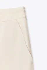 Pantalón palazzo color crema, de tiro alto, con bolsillos laterales y nervio marcado en el frente.