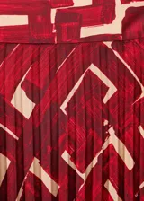 Falda midi plisada de tejido fluido con estampado abstracto en tonos rojo y beige.