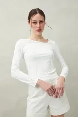 Top blanco de manga larga con escote asimétrico.