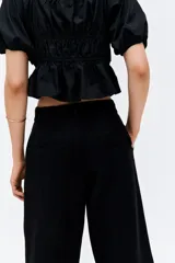 Pantalón negro de lino, de tiro alto, corte ancho y bolsillos laterales.
