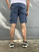 Bermuda de gabardina color marrón claro, corte recto, con bolsillos cargo laterales y bolsillos traseros con solapa.