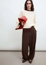Sweater color crema de tejido de punto trenzado, con cuello redondo y mangas acampanadas.